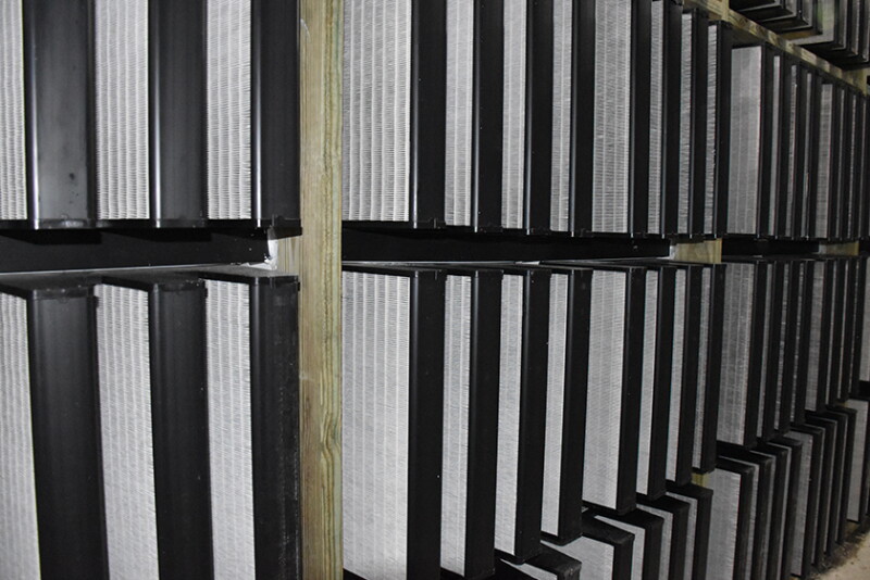 Installed filter wall with V-bank filters seated in grids across a barn endwall